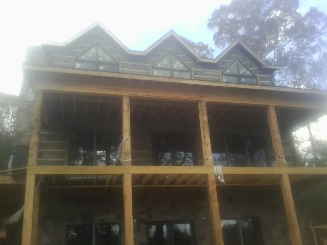 Dormers and porch framing on a large log home under construction — Roof Coating work by our crew in Forest City