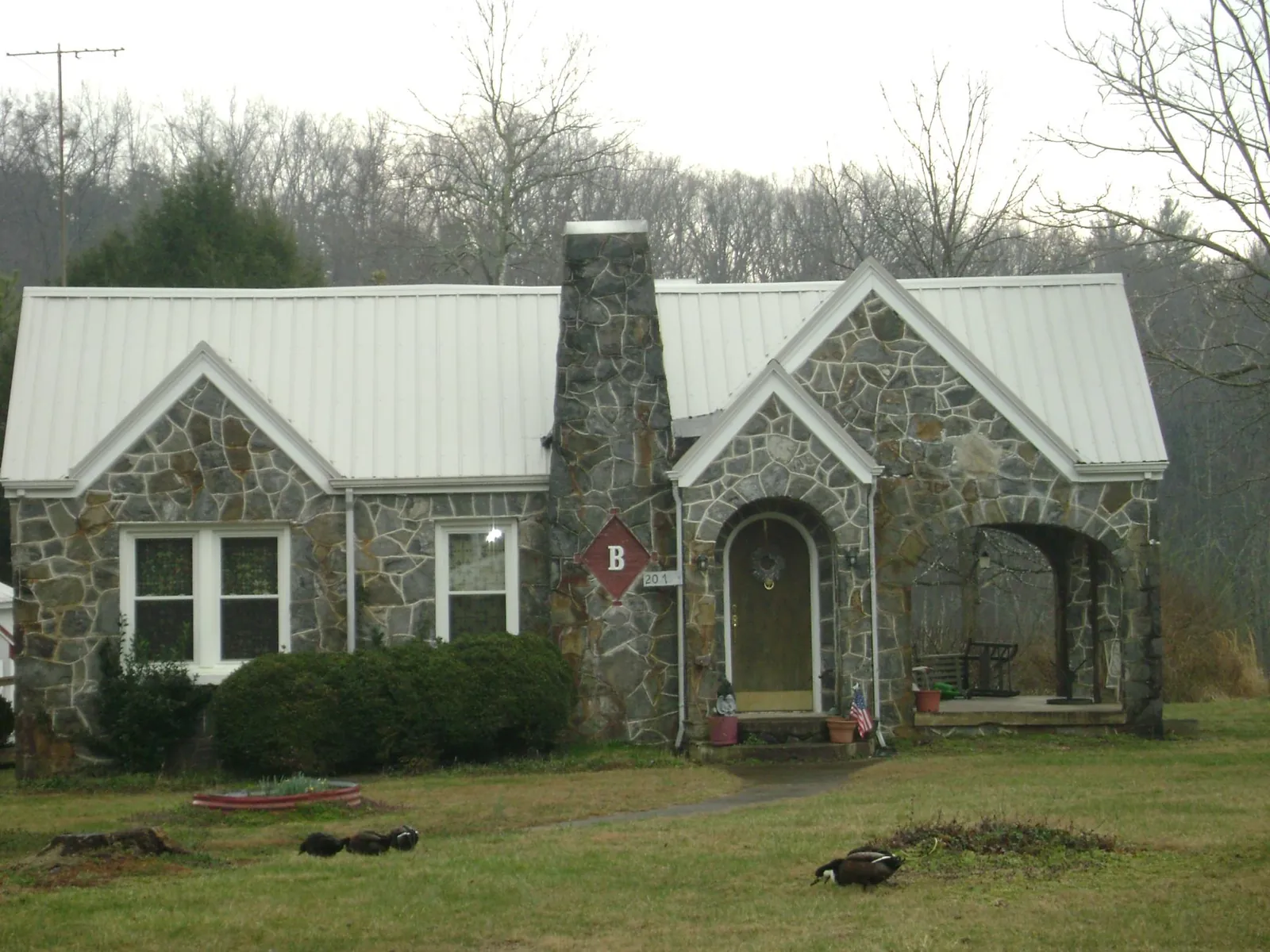 White metal roof on a stone cottage with steep gables in Forest City